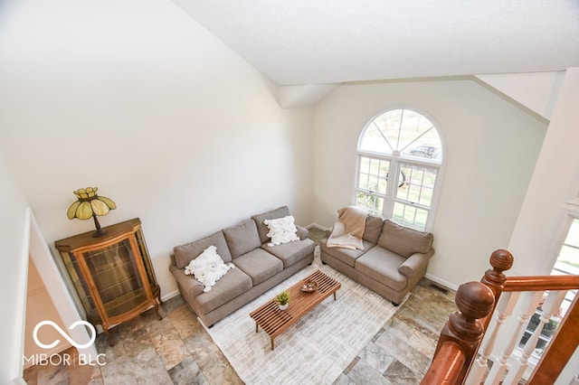 living area with lofted ceiling, stone finish floor, visible vents, and baseboards