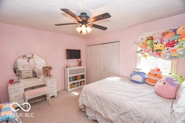 bedroom featuring a closet, light carpet, ceiling fan, and a textured ceiling