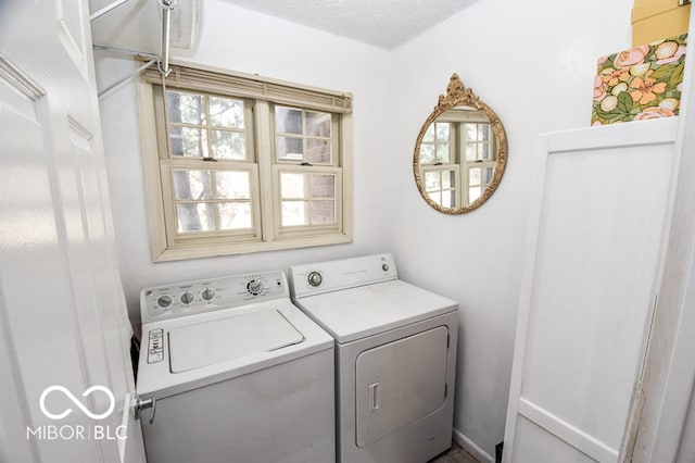 clothes washing area with a textured ceiling, laundry area, and washing machine and clothes dryer