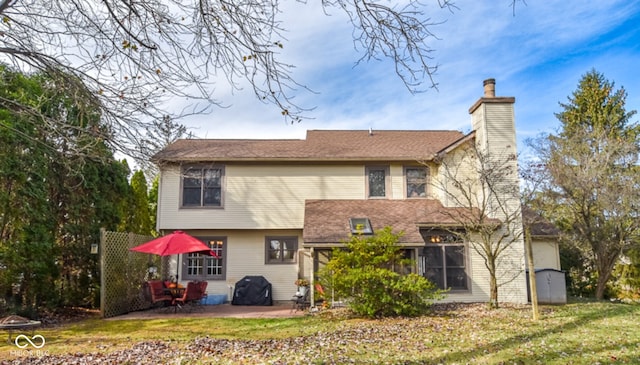 rear view of house with a patio area, a lawn, and a chimney