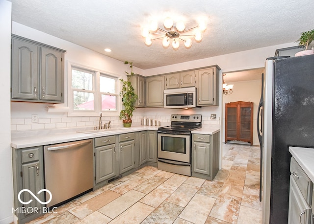 kitchen with a chandelier, stainless steel appliances, a sink, and light countertops