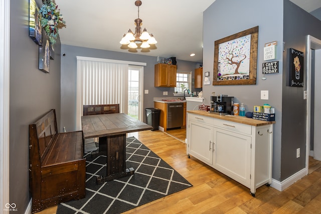 kitchen featuring white cabinets, hanging light fixtures, stainless steel dishwasher, light wood-type flooring, and a chandelier