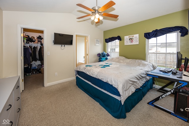 bedroom with a walk in closet, a closet, multiple windows, and lofted ceiling