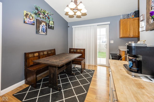 dining space with a chandelier, wood-type flooring, and lofted ceiling