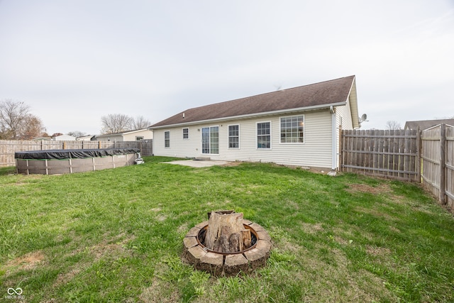 back of property featuring a fire pit, a covered pool, and a lawn