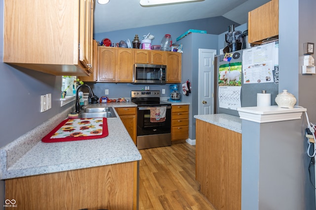 kitchen featuring sink, stainless steel appliances, lofted ceiling, and light wood-type flooring