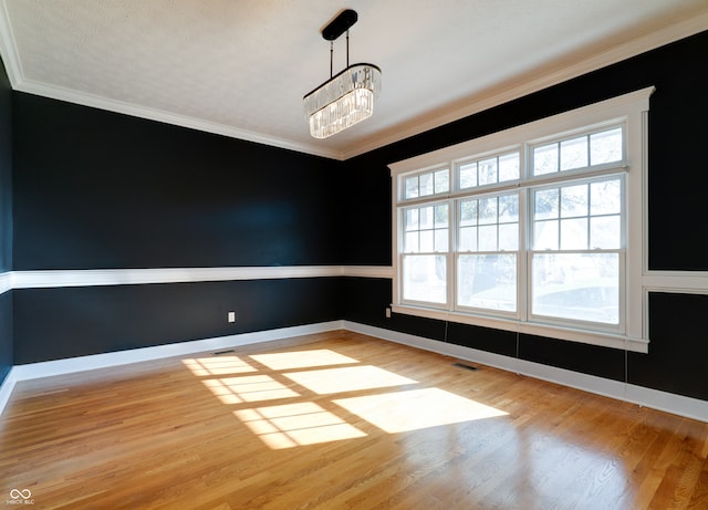 unfurnished dining area featuring light wood-type flooring, an inviting chandelier, ornamental molding, and a textured ceiling