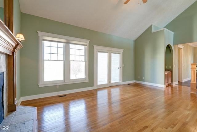 7290 Lockford Walk N, Avon, IN 46123 - unfurnished living room featuring a tiled fireplace, arched walkways, a ceiling fan, light wood finished floors, and baseboards
