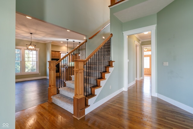 stairway featuring a chandelier, hardwood / wood-style flooring, and ornamental molding