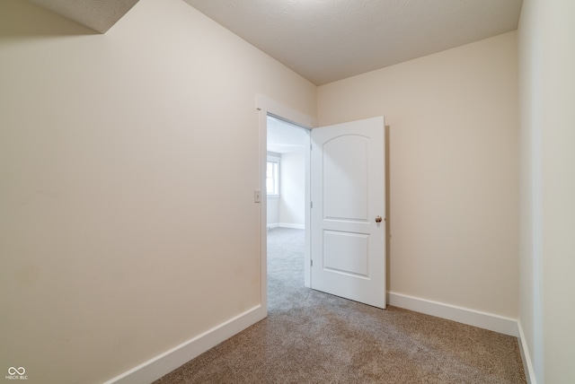 unfurnished room with a textured ceiling and light carpet