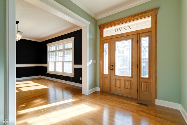 entryway with a notable chandelier, crown molding, and light hardwood / wood-style flooring