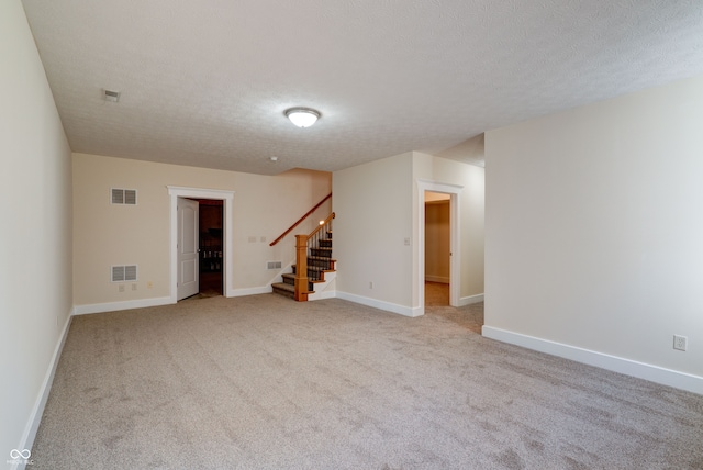 spare room featuring a textured ceiling and light carpet