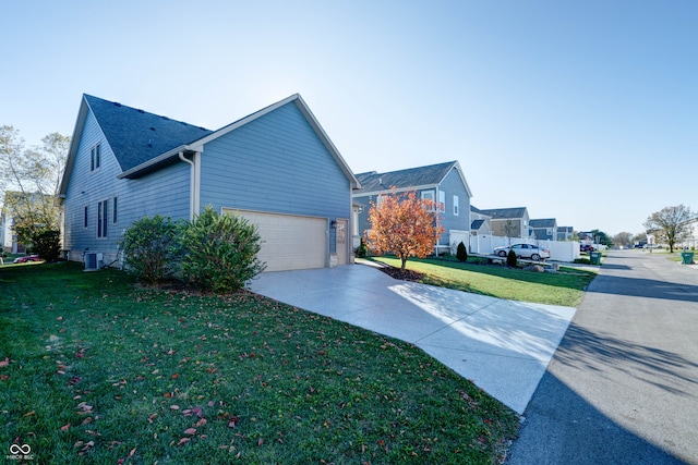 view of front of home featuring a garage, cooling unit, and a front yard