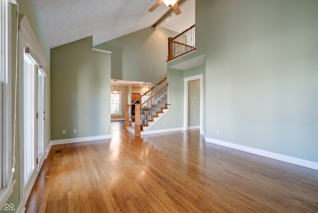 interior space with ceiling fan, a textured ceiling, light hardwood / wood-style flooring, and high vaulted ceiling