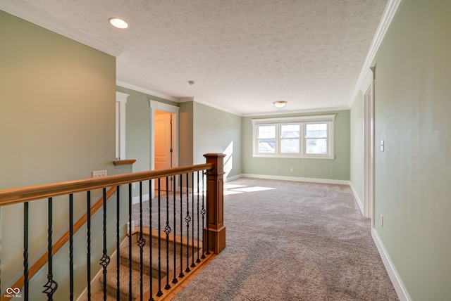 hallway featuring a textured ceiling, crown molding, and carpet