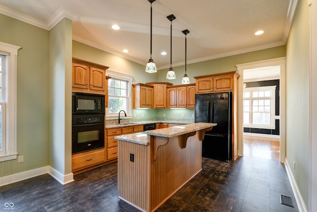 kitchen featuring light stone counters, a center island, black appliances, ornamental molding, and pendant lighting