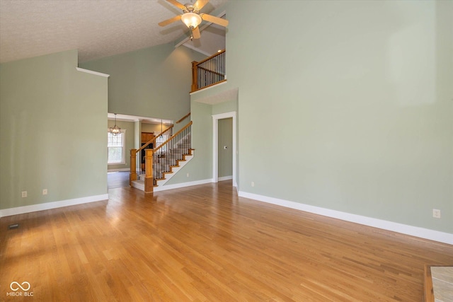 7290 Lockford Walk N, Avon, IN 46123 - unfurnished living room with stairway, a chandelier, a ceiling fan, light wood-type flooring, and high vaulted ceiling