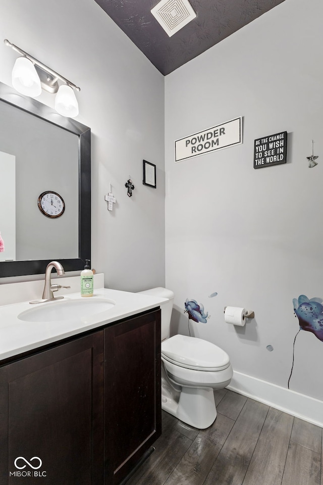 bathroom with toilet, vanity, a textured ceiling, and hardwood / wood-style flooring