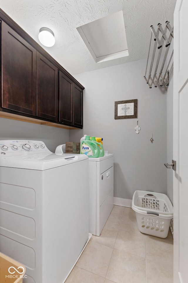 washroom featuring cabinets, a textured ceiling, washer and clothes dryer, and light tile patterned flooring