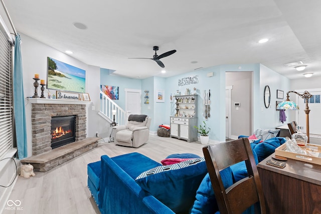 living room featuring ceiling fan, light wood-type flooring, and a fireplace