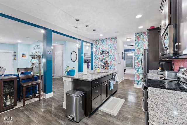 kitchen with light stone countertops, appliances with stainless steel finishes, dark hardwood / wood-style flooring, and hanging light fixtures