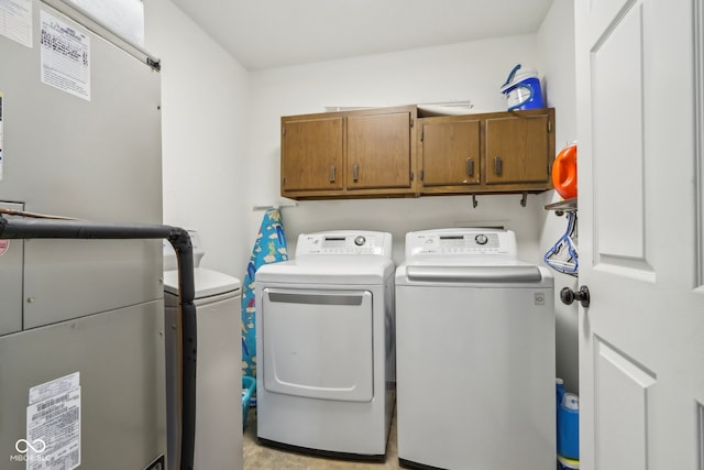 laundry room with heating unit, cabinets, and separate washer and dryer