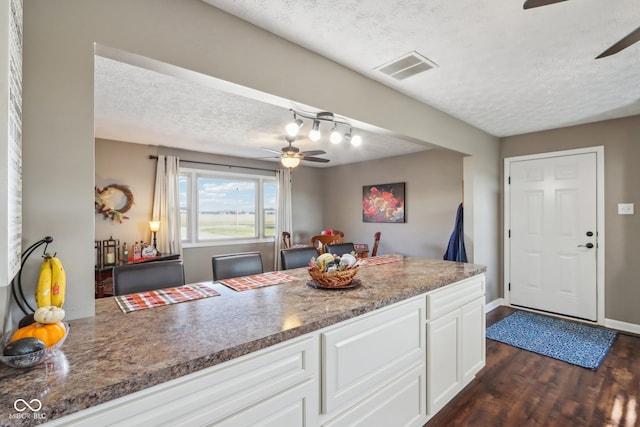 kitchen with dark stone counters, a textured ceiling, dark hardwood / wood-style floors, white cabinets, and ceiling fan