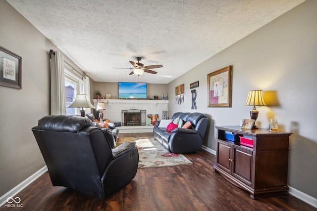 living room with dark hardwood / wood-style flooring, a textured ceiling, ceiling fan, and a fireplace