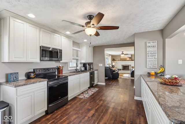 kitchen with black appliances, dark stone counters, a textured ceiling, white cabinets, and dark wood-type flooring