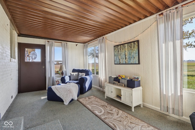 sitting room featuring carpet flooring, brick wall, and wood ceiling