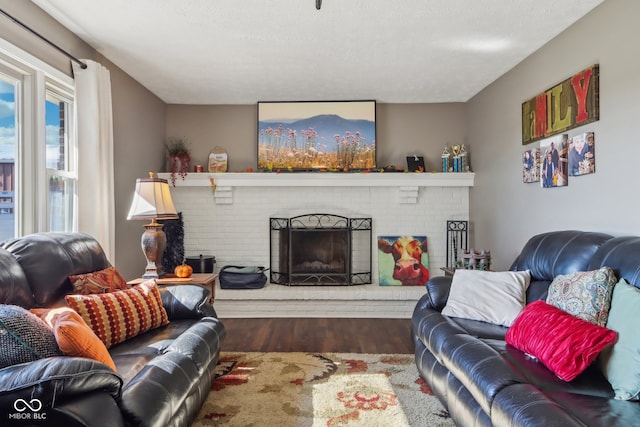 living room featuring a brick fireplace, dark wood-type flooring, and a textured ceiling