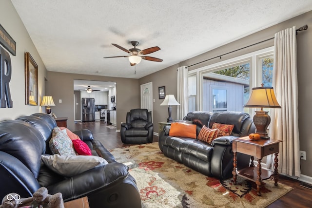 living room with ceiling fan, a textured ceiling, and dark hardwood / wood-style floors