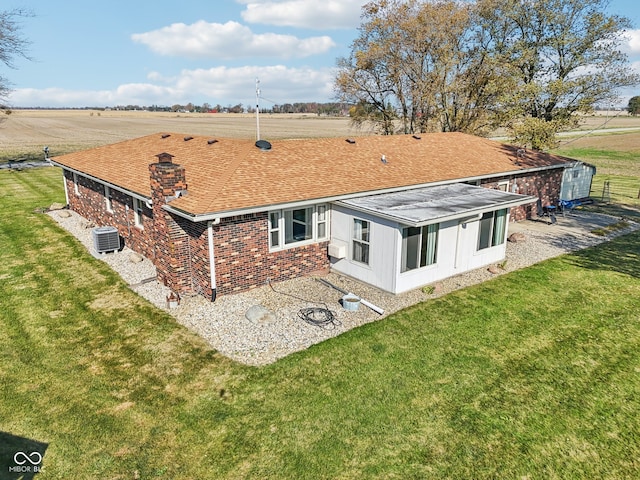 back of house featuring central AC unit, a rural view, and a yard