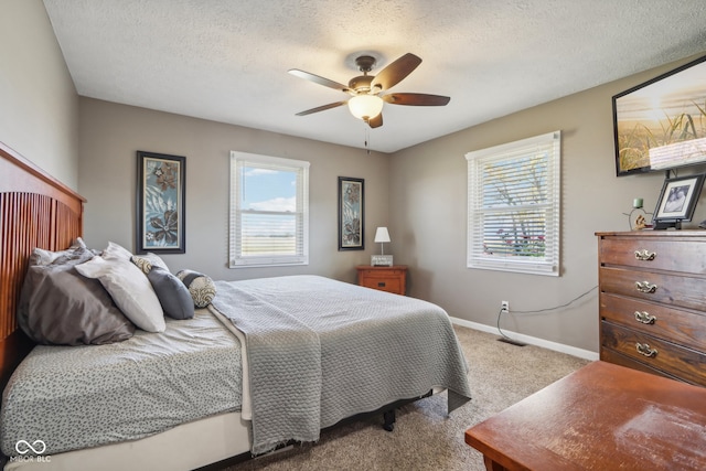 carpeted bedroom featuring ceiling fan and a textured ceiling