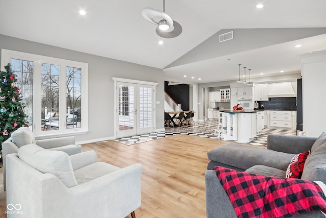 living room featuring french doors, lofted ceiling, and light hardwood / wood-style flooring