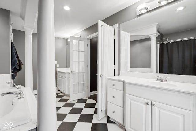 bathroom featuring a washtub, ornate columns, and vanity