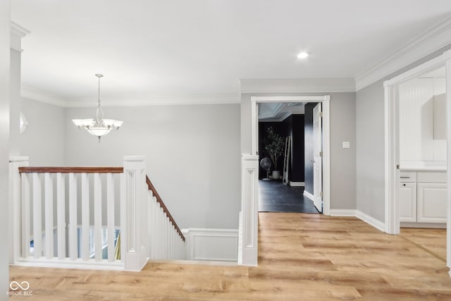 corridor with a chandelier, light hardwood / wood-style floors, and ornamental molding