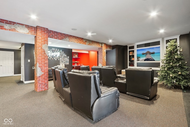 carpeted home theater room featuring decorative columns and brick wall