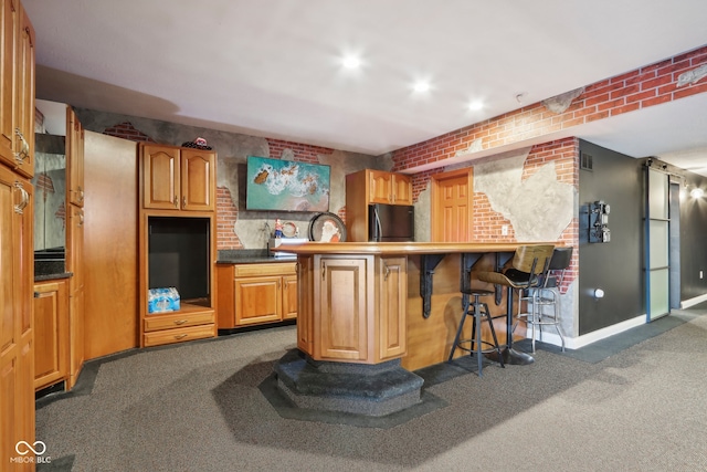 bar featuring dark colored carpet, black fridge, and brick wall