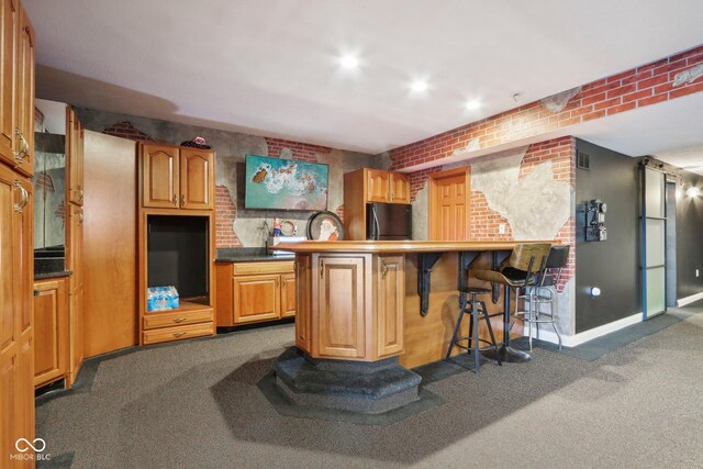 5784 N 600 E, Greenfield, IN 46140 - kitchen with dark colored carpet, freestanding refrigerator, a kitchen bar, brick wall, and baseboards