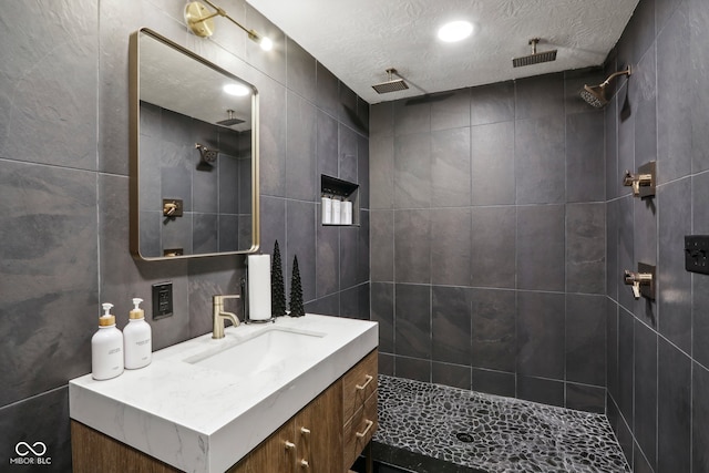 bathroom with vanity, a textured ceiling, and tiled shower