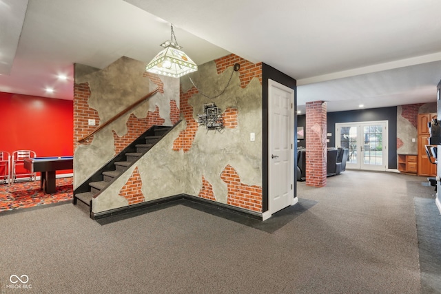 interior space with decorative columns, french doors, and brick wall