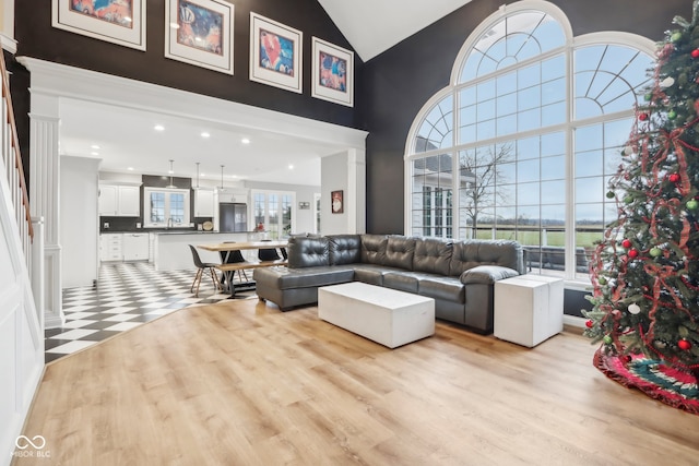 living room featuring light hardwood / wood-style floors, high vaulted ceiling, and decorative columns