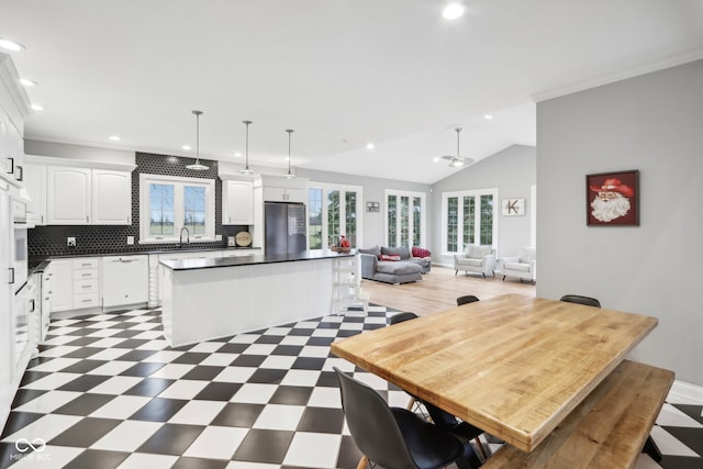 kitchen featuring decorative backsplash, stainless steel fridge, white cabinets, a center island, and hanging light fixtures