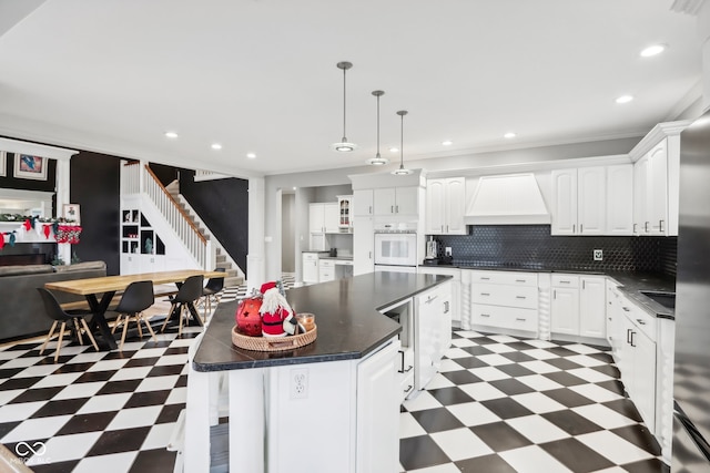 kitchen featuring white oven, white cabinetry, a center island, and pendant lighting