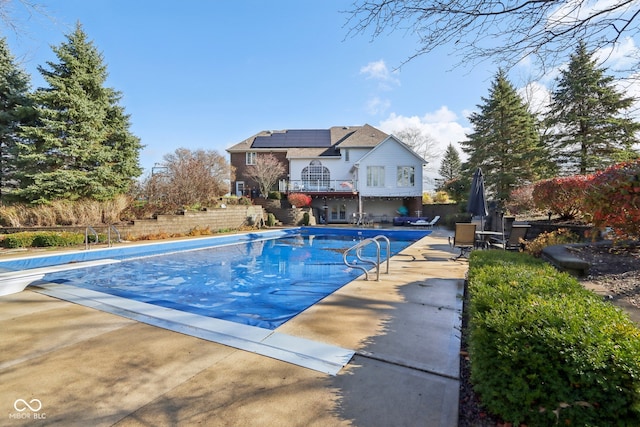 view of swimming pool featuring a diving board and a patio area