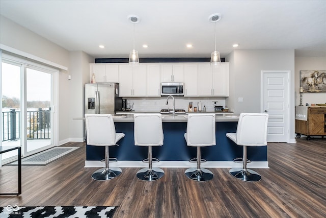 7282 Zanesville Rd, Carmel, IN 46033 - kitchen featuring appliances with stainless steel finishes, a breakfast bar area, backsplash, light countertops, and an island with sink
