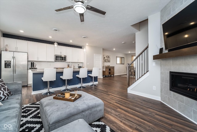 7282 Zanesville Rd, Carmel, IN 46033 - living area with dark wood-type flooring, stairway, a fireplace, a ceiling fan, and baseboards
