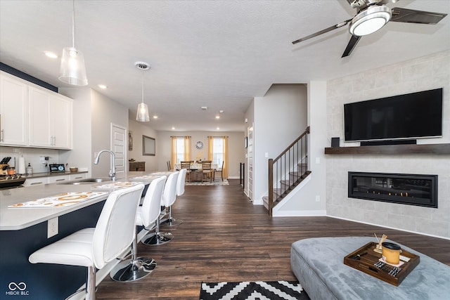 7282 Zanesville Rd, Carmel, IN 46033 - interior space with stairs, ceiling fan, dark wood-style floors, baseboards, and a tile fireplace