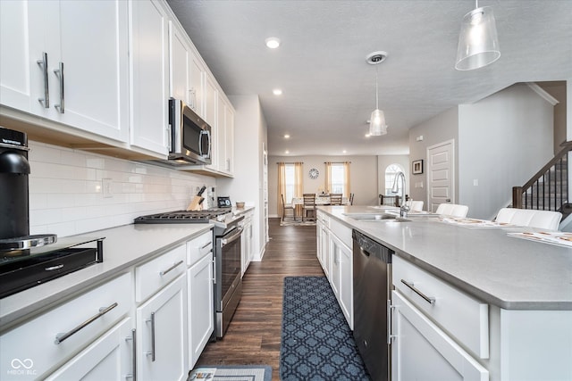 7282 Zanesville Rd, Carmel, IN 46033 - kitchen featuring dark wood-style flooring, a sink, decorative backsplash, white cabinets, and appliances with stainless steel finishes